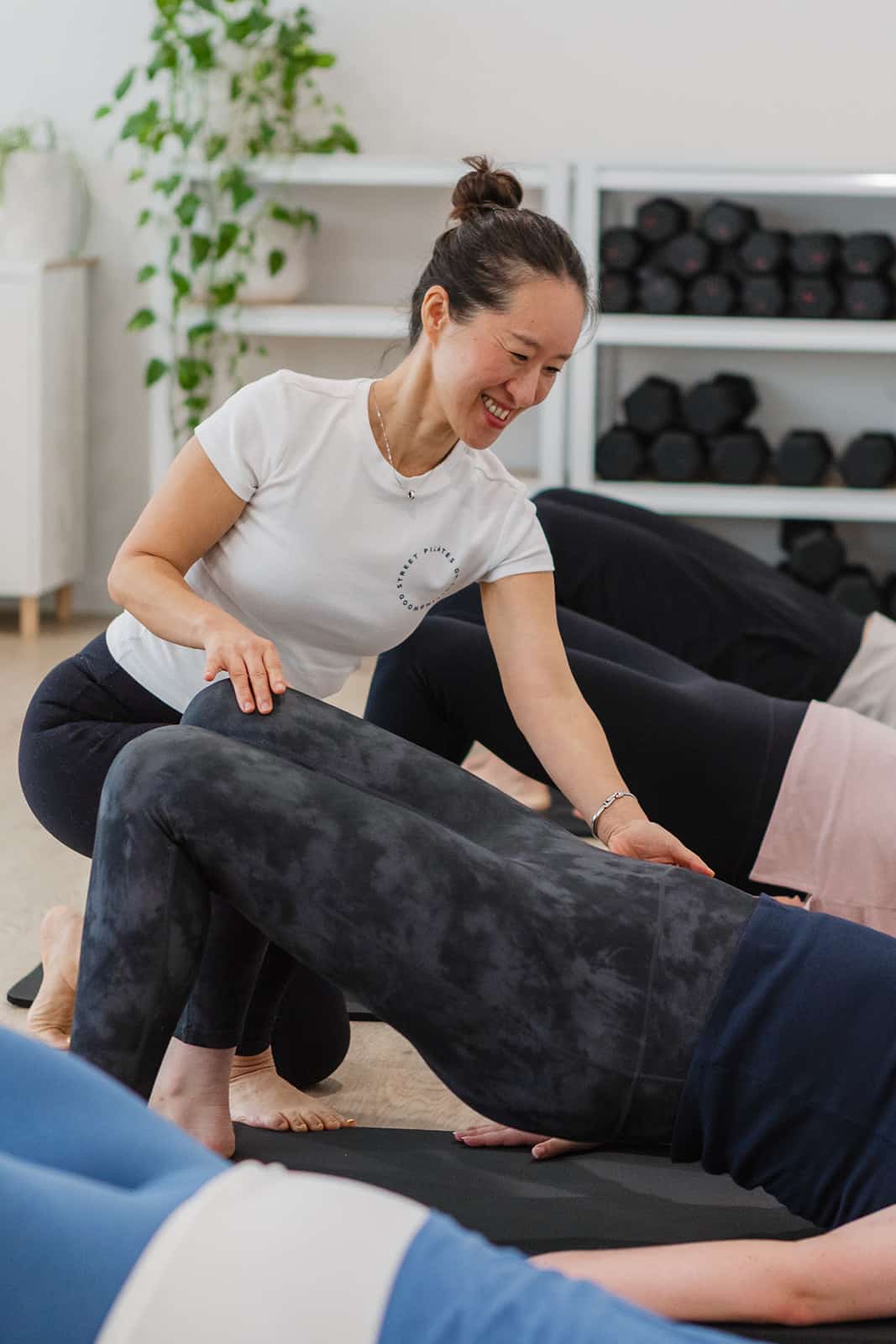 Pilates instructor providing hands-on guidance during a floor class at Pilates on Collingwood Street, Albion Brisbane